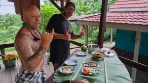 two men standing in front of a table of food at The Ridge Surf Lodge in Biha