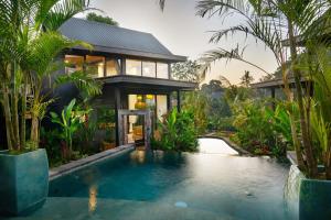 une maison avec une piscine devant une maison dans l'établissement Lorel Green Domain Ubud, à Ubud