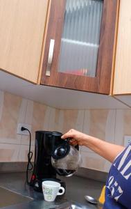 a person is pouring coffee into a coffee maker at Casa Ambrosía Eje Cafetero in Pereira