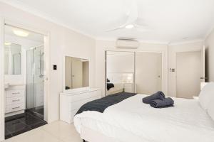 a white bedroom with a bed and a mirror at Tugun Tides in Gold Coast