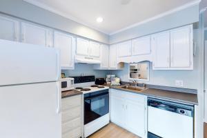 a kitchen with white cabinets and a white refrigerator at Southwinds I1 in Atlantic Beach +7 photos