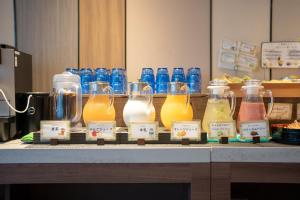 松本市にあるTabino Hotel lit Matsumoto Milky white Onsenのカウンターの上に置かれたオレンジジュースのガラス瓶の束