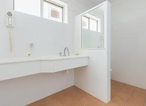 une salle de bain blanche avec un lavabo et un miroir dans l'établissement Busselton Motel, à Busselton