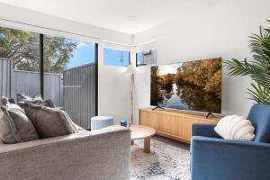 a living room with a couch and a large screen tv at Station & Surf 3BR Wollongong Townhouse in Wollongong