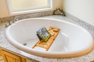 una vasca da bagno bianca con un bicchiere di vino e un libro di Beaver Pines Central Hiking Camp on Budget a Beaver Altre 19 foto