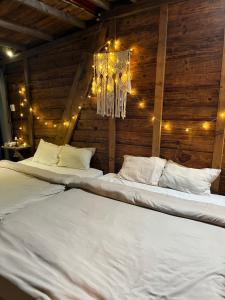 two white beds in a room with a chandelier at Nhà Tĩnh - Tiệm Cà phê Tĩnh 2 in Ấp Ða Lợi