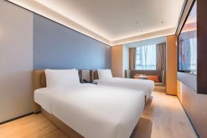 a hotel room with two beds and a television at Orange Hotel Beijing Beiqing Road Zhongguancun Eco-friendly Park in Beijing