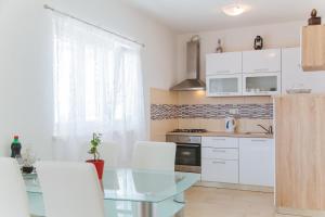 een keuken met een glazen tafel en witte kasten bij Apartment Chiara in Dugi Rat