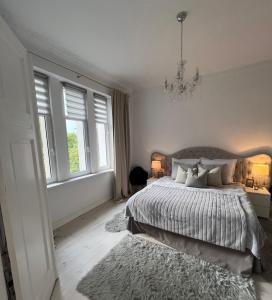 a bedroom with a bed and a chandelier and windows at APARTAMENT PARYSKI, Centrum Słupsk in Słupsk