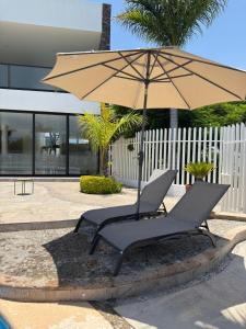 two chairs under an umbrella next to a pool at Casa de Campo Lake Shore Jocotepec in San Cristóbal Zapotitlán