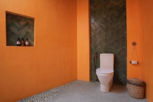 a bathroom with a toilet in an orange wall at Marshmallow Bay Boutique Hotel & Surf Point Adults Only in Ahangama