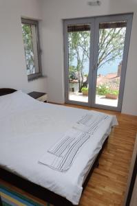 a white bed in a room with two windows at Maslov Apartments in Ohrid