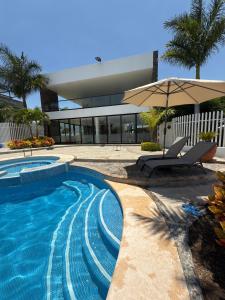 a swimming pool with a chair and an umbrella at Casa de Campo Lake Shore Jocotepec in San Cristóbal Zapotitlán