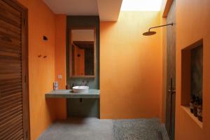 an orange bathroom with a sink and a mirror at Marshmallow Bay Boutique Hotel & Surf Point Adults Only in Ahangama