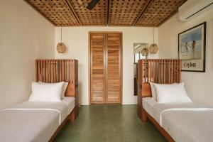 two beds sitting in a room with a room with a door at Marshmallow Bay Boutique Hotel & Surf Point Adults Only in Ahangama