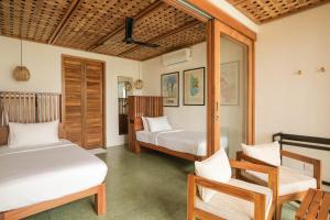 a bedroom with two beds and a chair at Marshmallow Bay Boutique Hotel & Surf Point Adults Only in Ahangama