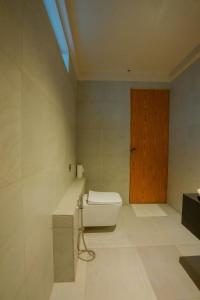 een badkamer met een toilet en een houten deur bij Turtle Nest in Tangalle