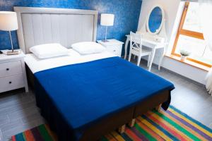 a bedroom with a blue and white bed and a desk at Vila Nikolas in Druskininkai