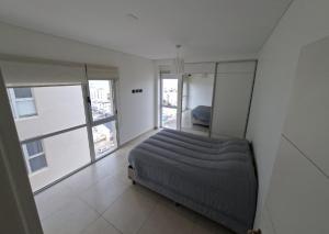 a bedroom with a bed in a room with windows at Espacio Chacabuco in Comodoro Rivadavia