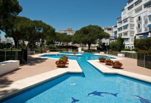 a large swimming pool with potted plants next to a building at Beachside Luxury Apartment in Puerto Banus - Club Playas del Duque in Marbella