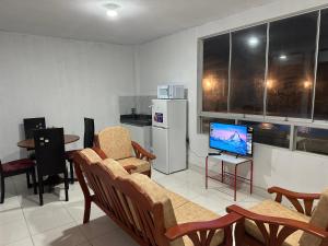 a living room with chairs and a tv and a kitchen at CAMPO AZUL Cerro Azul in Cerro Azul