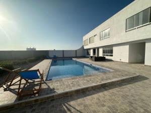a chair and a swimming pool next to a building at CAMPO AZUL Cerro Azul in Cerro Azul