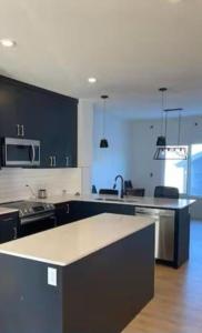 a kitchen with black cabinets and a counter top at Bedroom with TV in Upland E in Edmonton