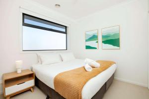 a white bedroom with a bed and a window at Northside Townhouse Geelong in Norlane