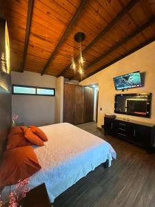 a bedroom with a bed and a flat screen tv at Cabaña DAGO in Mazamitla