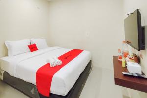 a bedroom with a bed with a red and white blanket at RedDoorz at Rejoss Lux Medan in Medan +20 photos