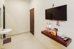 a bathroom with a sink and a television on a wall at RedDoorz at Rejoss Lux Medan in Medan