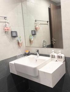 a bathroom with a white sink and a mirror at Honey Vinhomes in Long Bình