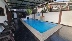 Una gran piscina en un edificio con sillas. en NEW!!! AURORA HIDEAWAY VILLA 35pax 7R7B PRIVATE POOL, KTV, BBQ, ARCADE GAMES, 5min to BEACH, en Port Dickson
