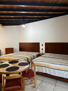 two beds in a room with a table and chairs at Posada "CASA BONITA" in La Cal
