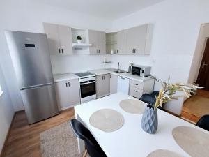a white kitchen with a table and a refrigerator at Apartmán v tichom prostredí blízko centra in Martin