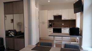 una cocina con armarios blancos y una mesa con sillas. en Tripiers Duplex, en Colmar