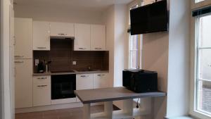 Una cocina con gabinetes blancos y una mesa y un televisor. en Tripiers Duplex, en Colmar 6 fotos más