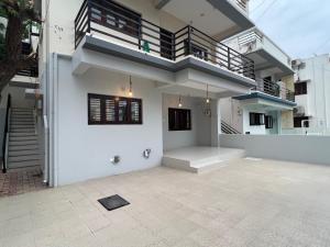 a white house with a staircase and a balcony at Nisarg Homestay with Kitchen Dinning in Bhuj