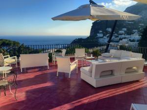 eine Terrasse mit einem Tisch, Stühlen und einem Sonnenschirm in der Unterkunft Villa Silia in Capri