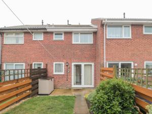 an exterior view of a brick house with a wooden fence at Wren Cottage in Weymouth