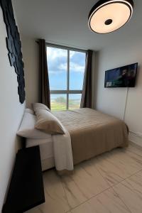 a bedroom with a bed and a large window at Vista al Mar y Ciudad de 2 habitaciones in Panama City