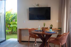 ein Esszimmer mit einem Tisch und einem TV an der Wand in der Unterkunft Studio Alva na Praia de Lages, Rota dos Milagres in Tatuamunha