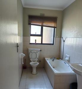 a bathroom with a tub and a toilet and a sink at GLOBALNEST guest house in Cape Town