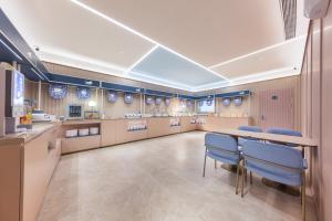 a large kitchen with a table and blue chairs at Hanting Hotel Beijing Guang'anmen in Beijing
