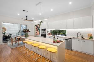 una cocina con armarios blancos y una barra con taburetes amarillos en Parkside Haven, en Toowoomba