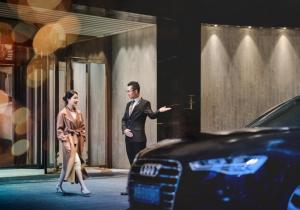 a man and woman walking down a street next to a car at The Azure Ningbo, Vignette Collection by IHG in Ningbo