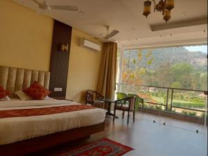 a hotel room with a bed and a large window at Palashgram Eco Resort in Bāghmundi