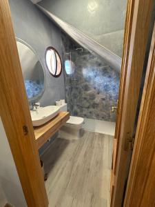a bathroom with a sink and a toilet and a mirror at Hostal Monica in Cilleruelo de Bezana