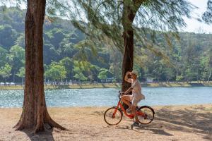 a woman riding a bike next to a tree at Sunsuri Phuket - SHA Plus in Nai Harn Beach