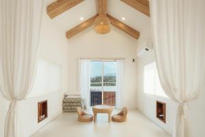ein Raum mit einem Tisch und Stühlen und einem Fenster in der Unterkunft Jeju Palm Spa Pool Villa in Jeju-do